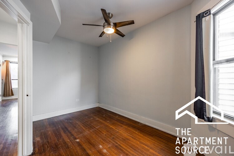A room with a ceiling fan and wooden floors.