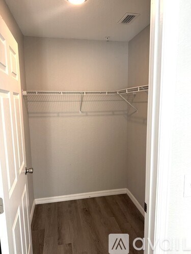 A white closet with a wooden floor and a white door.