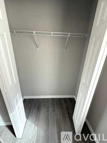 A white closet with a shelf and a door.