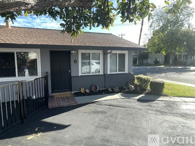 A house with a black door and windows is surrounded by a black fence.