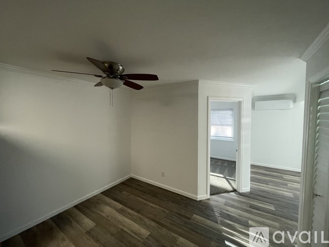 A room with a ceiling fan and wooden flooring.