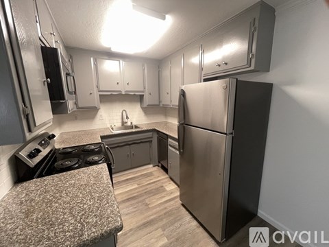 A kitchen with a refrigerator, stove, and cabinets.