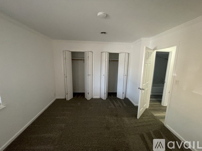 A carpeted room with a doorway leading to another room.