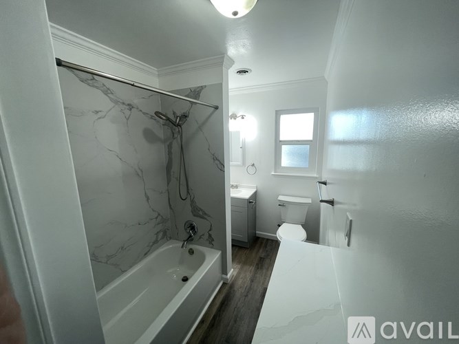 A bathroom with a marble tub surround and a toilet in the corner.