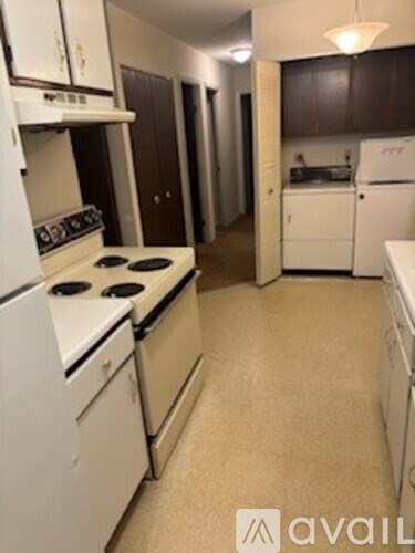 A kitchen with white appliances and brown cabinets.