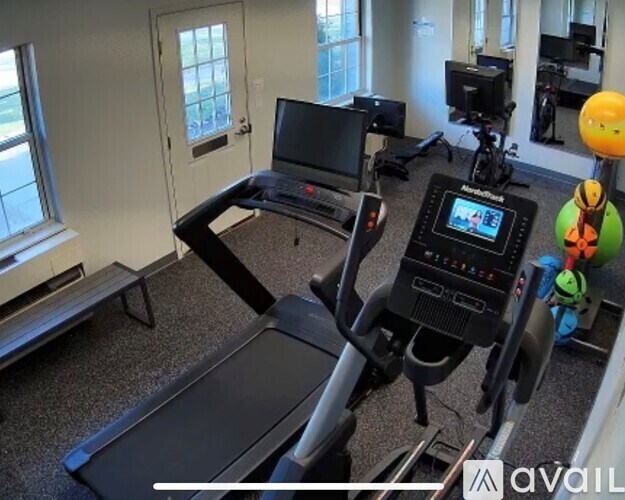 A treadmill with a screen and a bench in a room.