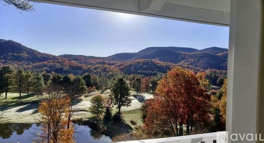 A view from a window looking out at a landscape with a pond and autumn trees.