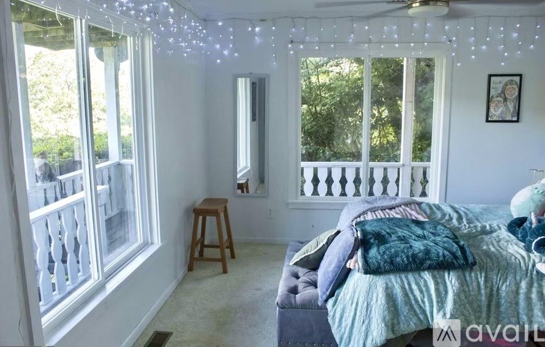 A bedroom with a bed, a chair, and a window with a view of the backyard.