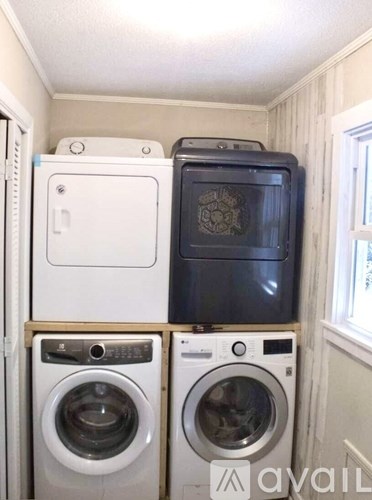 A stack of white and black appliances in a small room.