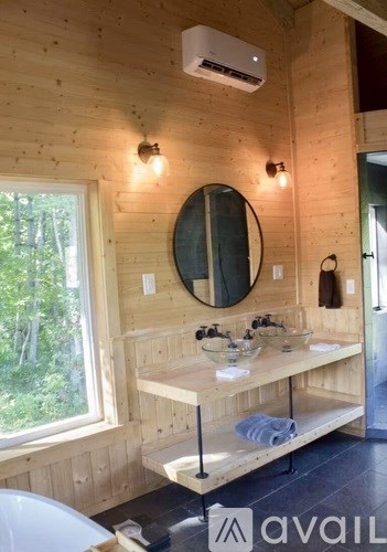 A bathroom with wooden walls and a round mirror above a sink.