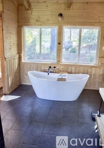 A white bathtub is in a bathroom with wooden walls.