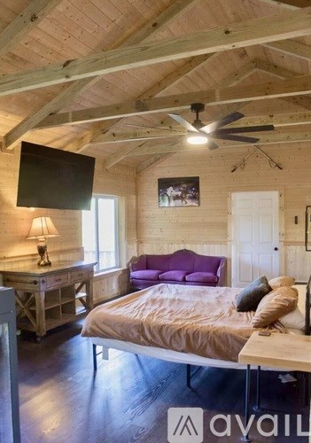 A bedroom with a bed, a dresser, and a ceiling fan.