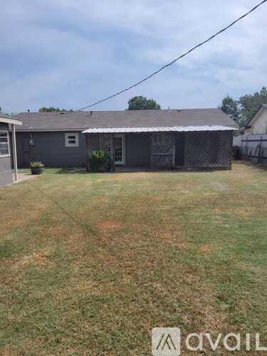 A house with a grey roof and a fence in front of it.