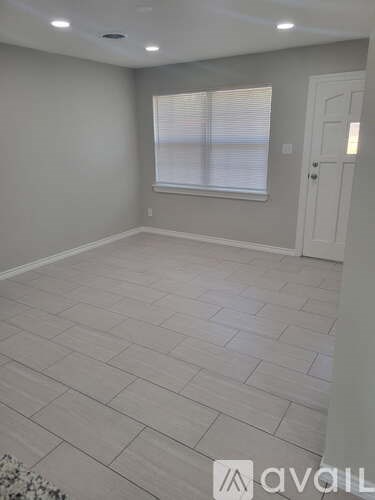 A room with a tiled floor and a window with blinds.