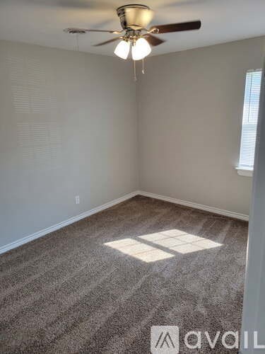 A room with a ceiling fan and carpeted floor.
