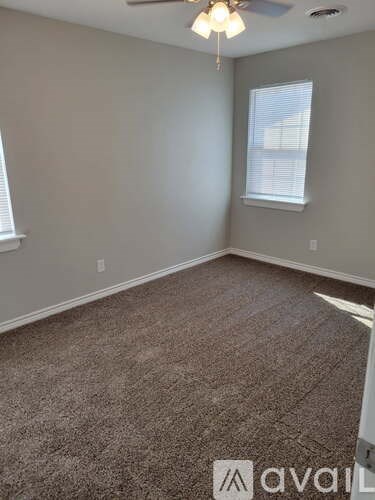 A room with a carpeted floor and a window with blinds.