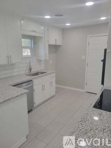 A kitchen with white cabinets and a granite countertop.