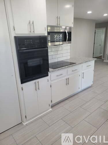 A kitchen with white cabinets and a black oven.