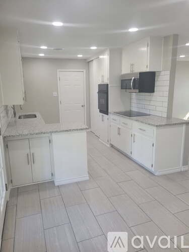 A kitchen with white cabinets and a black fridge.