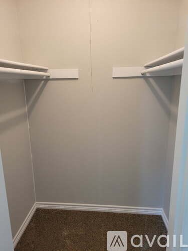 A small, empty room with a carpeted floor and two white shelves on the wall.
