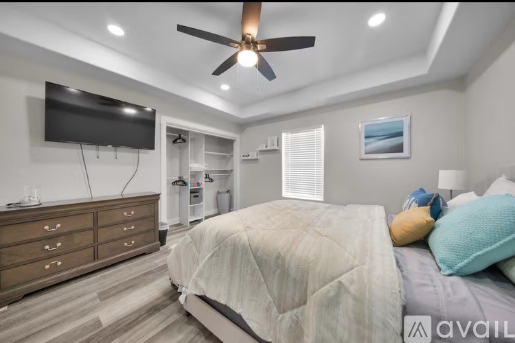A bedroom with a bed, dresser, and ceiling fan.