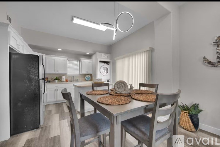 A kitchen with a table and chairs in the foreground and a refrigerator in the background.