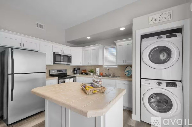 A kitchen with a refrigerator, microwave, oven, and washing machine.