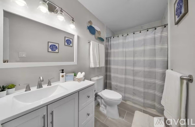 A bathroom with a white sink, toilet, and shower curtain.