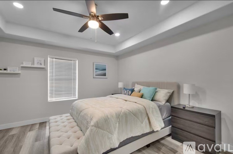 A bedroom with a bed, nightstand, and a ceiling fan.