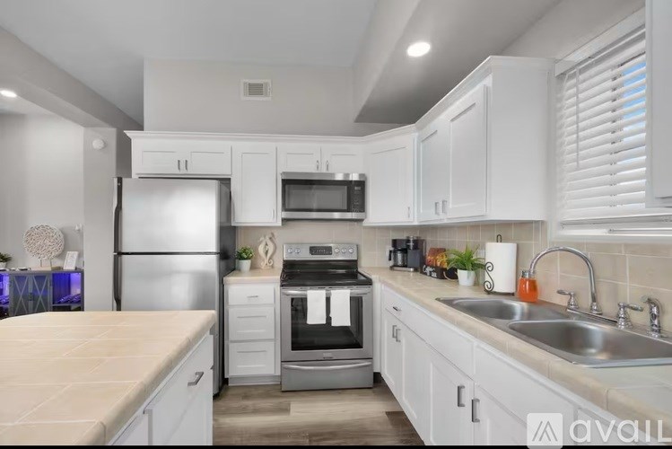 A modern kitchen with white cabinets and stainless steel appliances.