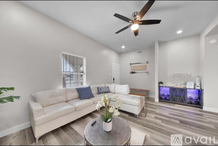 A living room with a white couch, a coffee table, and a ceiling fan.