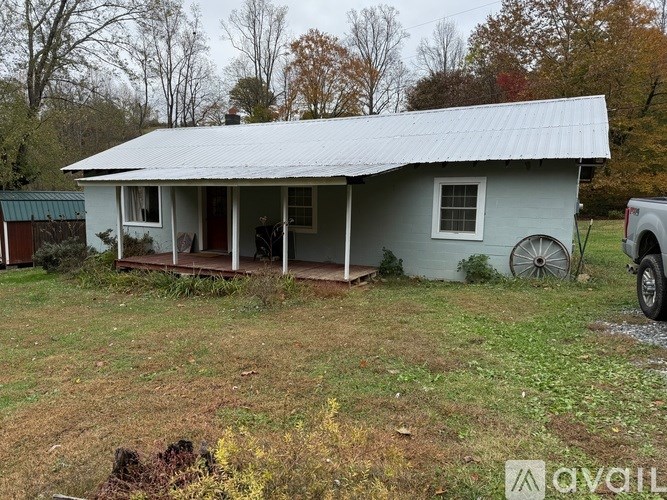 A small house with a porch and a truck parked in front.