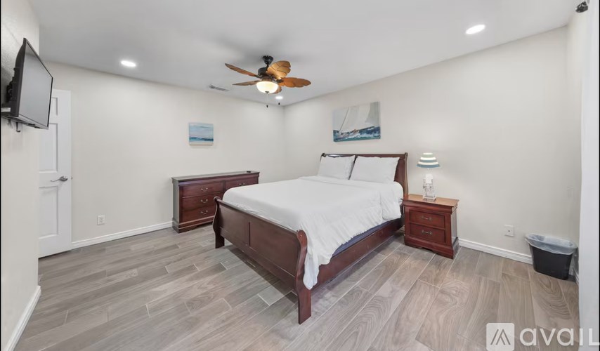 A bedroom with a bed, nightstand, and a ceiling fan.