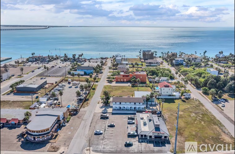 A bird's eye view of a coastal town with buildings, cars, and a body of water.