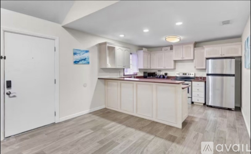 A kitchen with white cabinets and a wooden floor.
