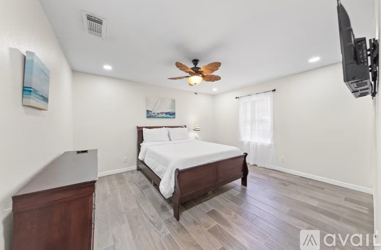 A bedroom with a bed, dresser, and television.