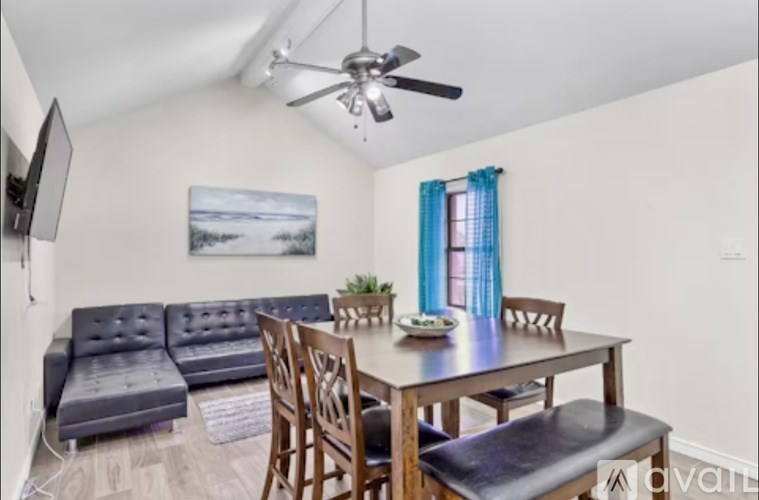 A living room with a grey sofa and a wooden dining table.