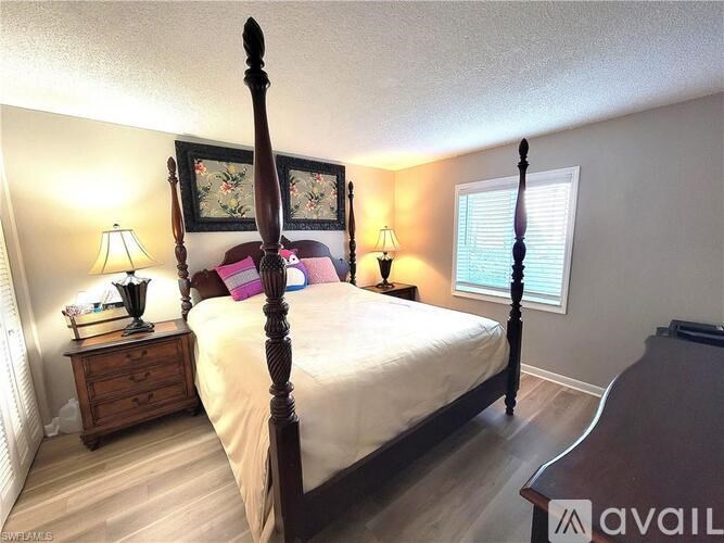 A bedroom with a four poster bed, a dresser and a window.