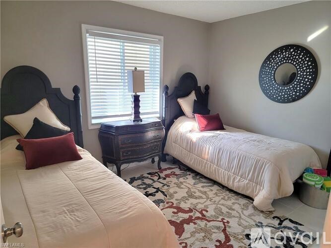 A bedroom with two beds, one with a red pillow and the other with a white pillow.