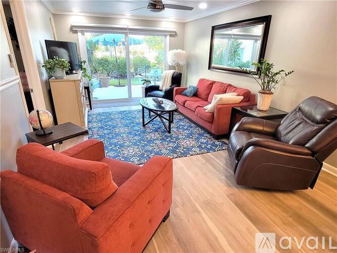 A living room with a red couch, a brown leather chair, and a blue rug.