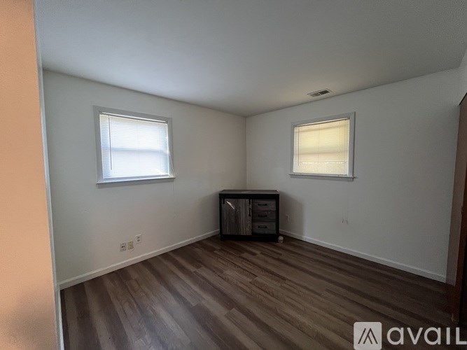 A room with wooden floors and two windows.