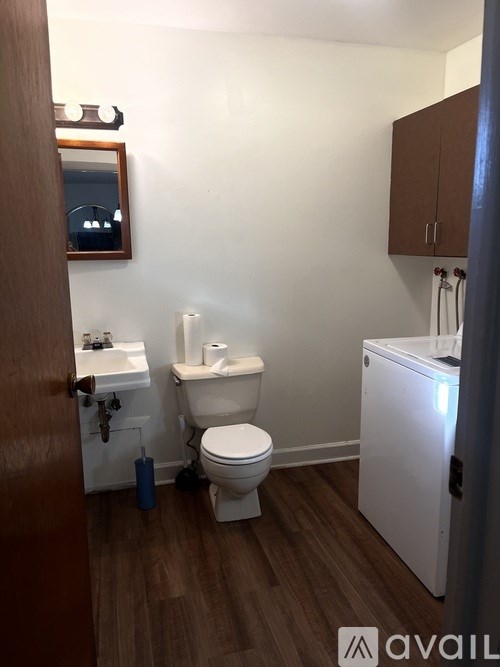 A small bathroom with a toilet, sink, and mirror.