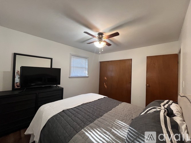 A bedroom with a bed, dresser, and television.
