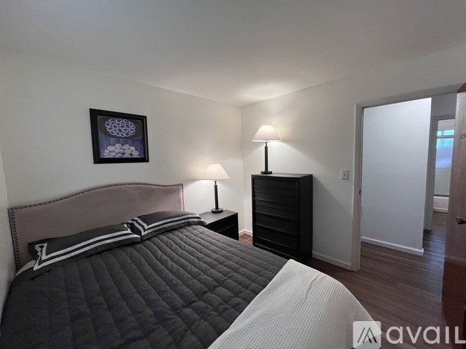 A bedroom with a large bed and a lamp on a side table.