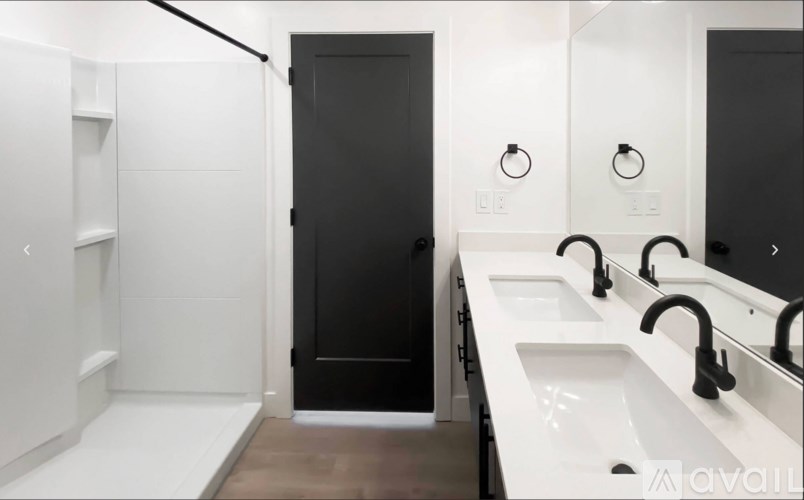 A bathroom with a black door and white sinks.