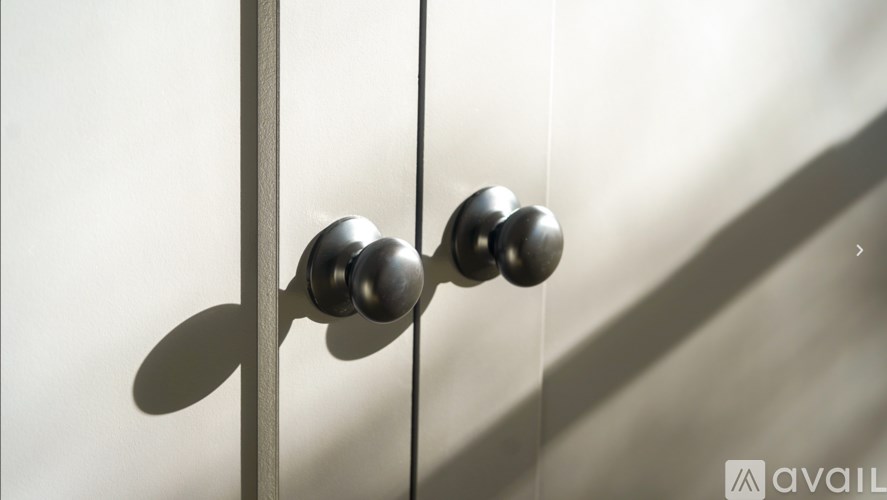 A close up of a metallic door handle on a white door.