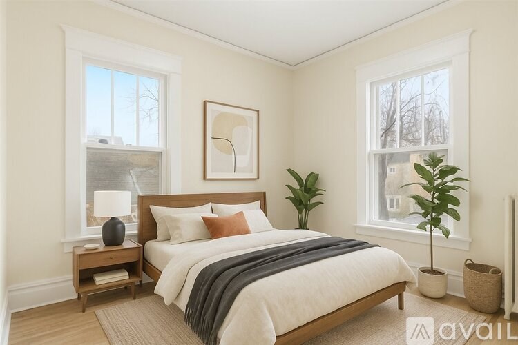 A bedroom with a large bed and a plant on the side table.