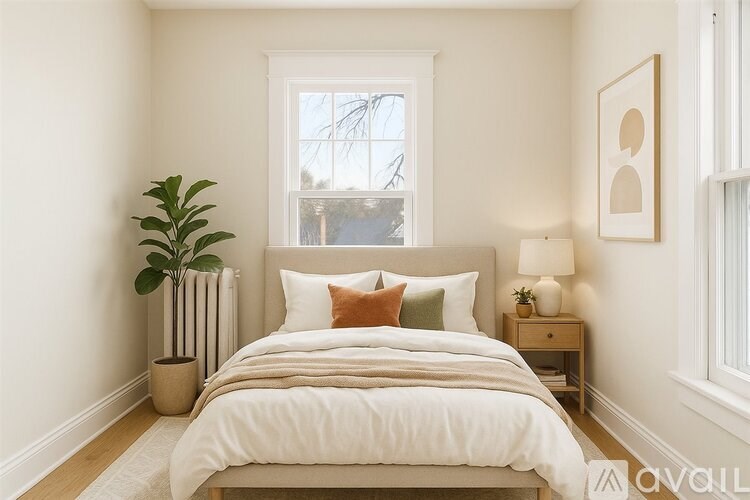 A bedroom with a large bed, a potted plant, and a window.