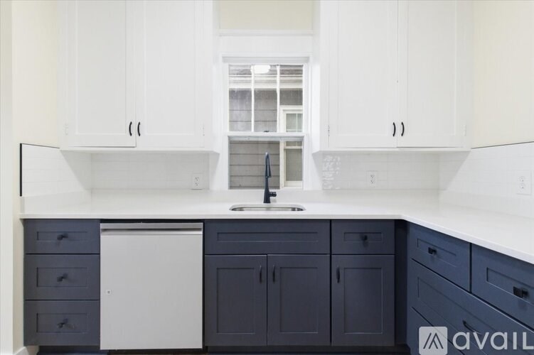A kitchen with white cabinets and dark blue drawers.