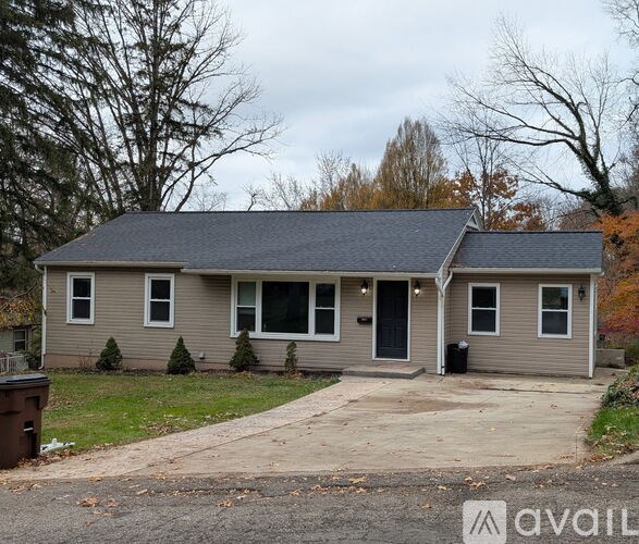 A house with a grey siding and a black door is available for rent.